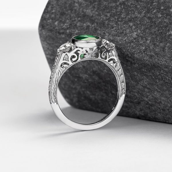 emerald engagement ring with filigree cut outs and hand engraving