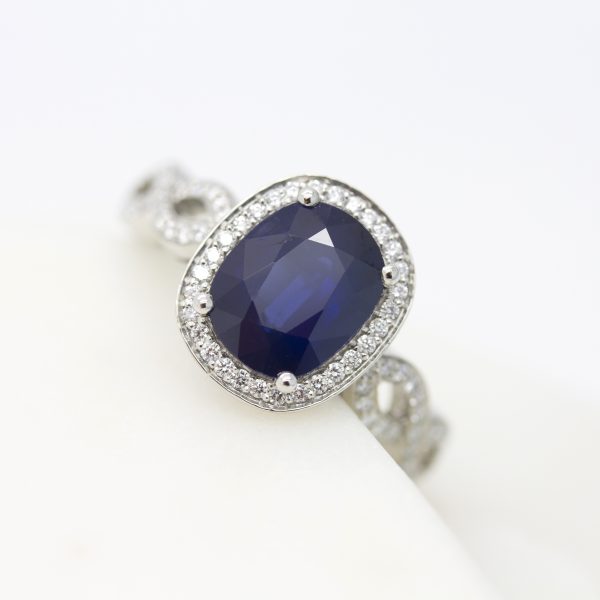 Oval blue sapphire with diamond halo and diamond pavé weaved band engagement ring set in platinum
