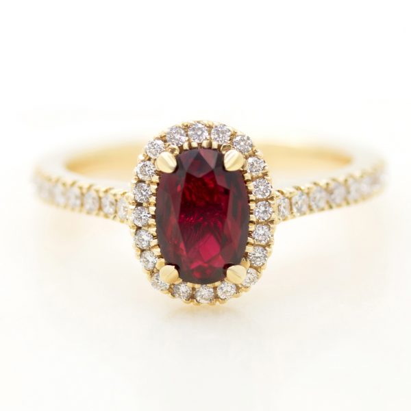 elongated oval ruby engagement ring with a yellow gold diamond halo