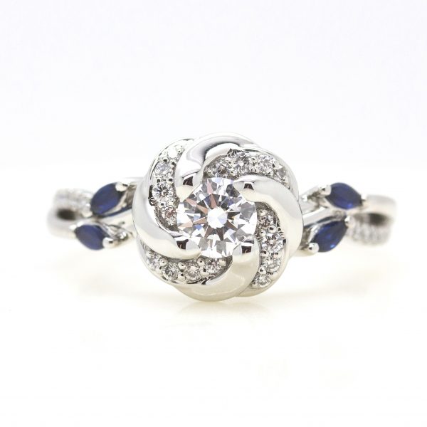 round diamond with pave swirl halo and split shank pave band with accent marquise blue sapphires