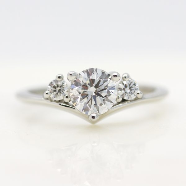 round diamond with round diamond accent stones and chevron platinum band engagement ring