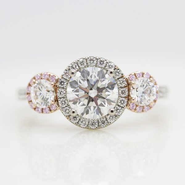 round diamond trilogy engagement ring with mixed metal and pink sapphire and diamond halo
