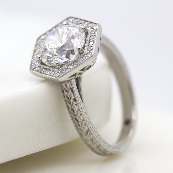 round diamond with hexagonal diamond halo and hand engraved band