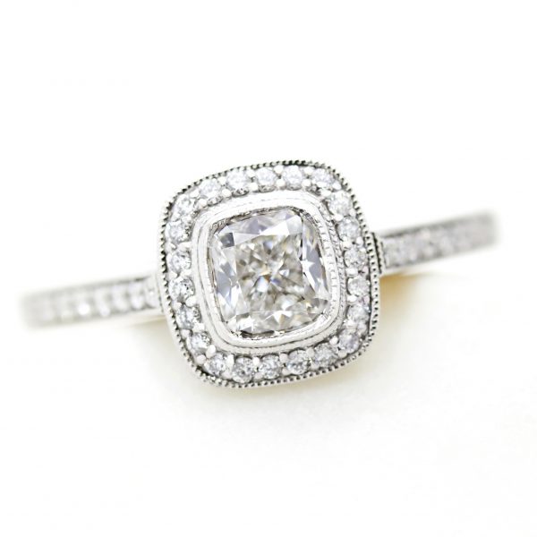 cushion cut diamond halo engagement ring with milgrain and bezel setting in platinum
